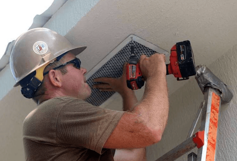 Man installing soffit vent on building